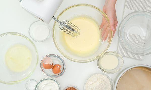 En håndmikser, bakeboller og egg oppstilt på et bord