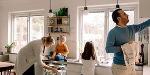 En familie på kjøkkenet tar ut rent servise fra oppvaskmaskinen.