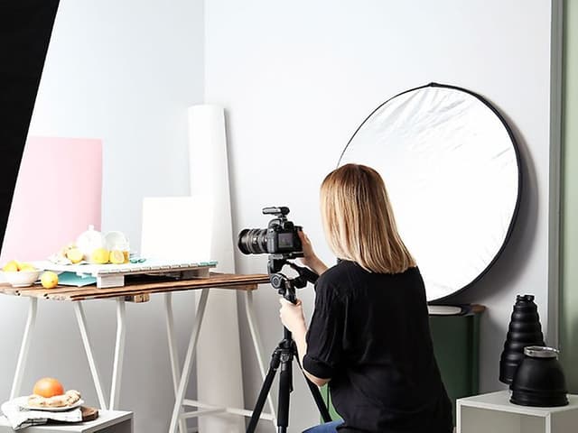 Kvinna som använder blixtar i en produktfotostudio