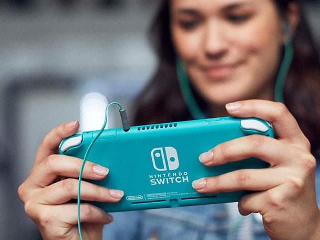 Leende kvinna spelar turkos Nintendo Switch Lite