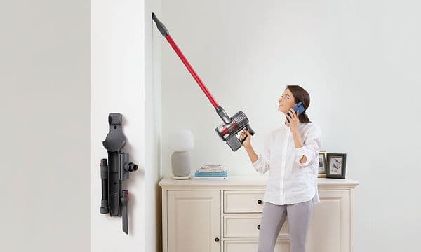 A woman using Roborock cordless stick vacuum to clean the wall