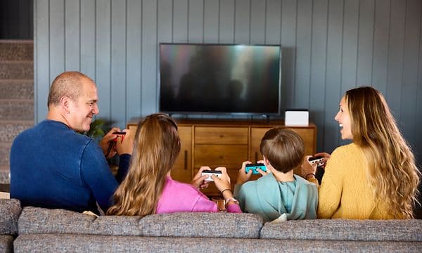 Familj sitter i soffa och spelar på Switch