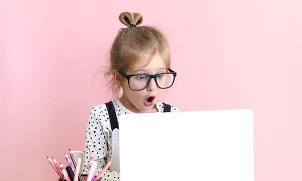 Yllättyneen näköinen tyttö kannettavan tietokoneen edessä