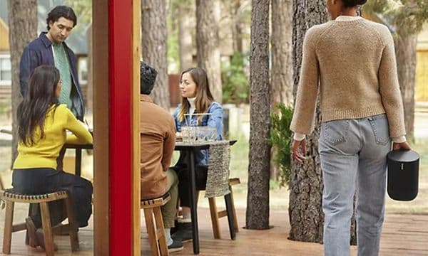 Kvinne som bærer Sonos Move forbi en forttauskafe