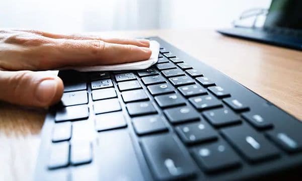 En person tørker av et tastatur med en klut