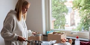 MDA-Frysare-Ung kvinna packar ut köksredskap ur lådor på ett bord vid ett fönster