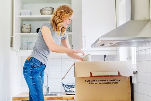 MDA-Frysar-Kvinna packar upp koppar ur en flyttlåda