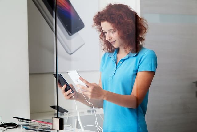 Ung kvinna håller i en smartphone i en butik
