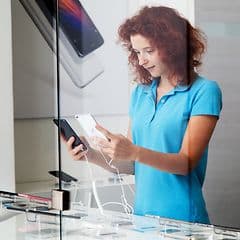 Ung kvinna håller i en smartphone i en butik
