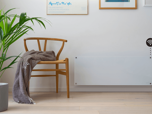 Smart panelovn på vegg med wifi-symbol og trestol og plante i front