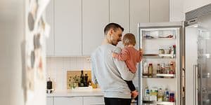 En pappa med sin dotter i ett kök bredvid en öppen kyl