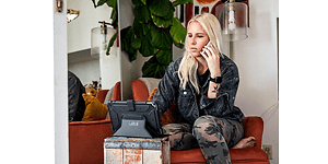 UAG skal och fodral till iPad- och surfplatta: En kvinna sitter i telefon och ser på sin padda med UAG fodral.