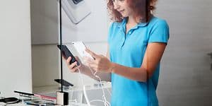 Ung kvinde sammenligner mobiltelefoner i butik