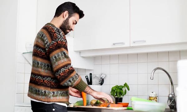 En mann lager mat på kjøkkenet