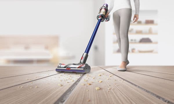 Kvinna som dammsuger golver med Dysons sladdlösa dammsugare
