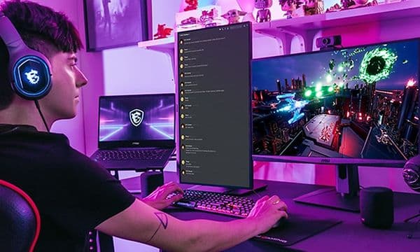 Gamer foran to skjermer og en bærbar pc