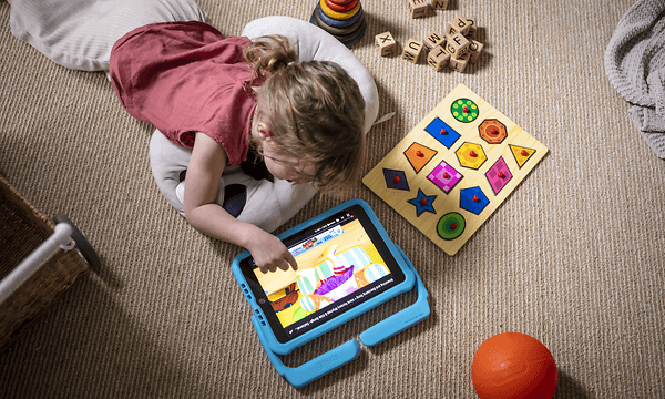 Två barn ligger på golvet och spelar på en iPad med Orlando-fodral