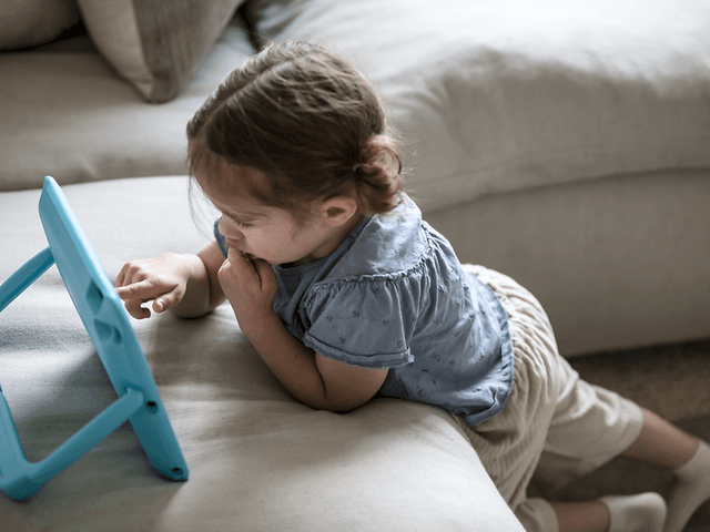 Litet barn med iPad som använder Orlando-fodral på en soffa
