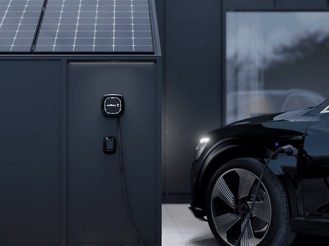 Wallbox på hus med solcellepanel og bil som lader