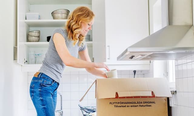 Kvinde tager glas ud af flyttekasse