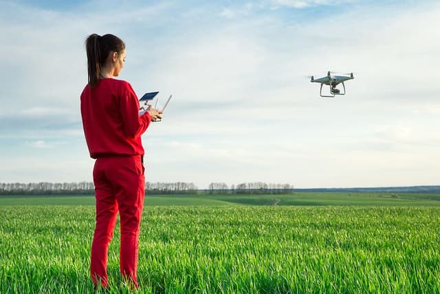 Nainen lennättää dronea avoimella kentällä