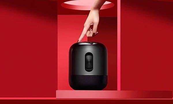 Ett finger trycker på en Huawei Sound X bärbar högtalare.