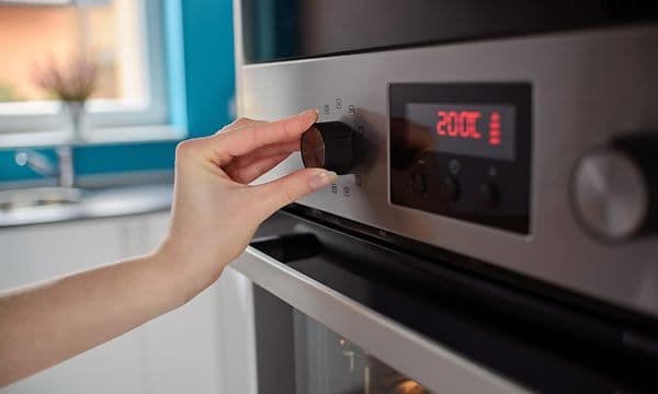 MDA - Hånd som justerer temperatur på stekeovn