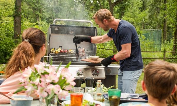 Perheen isä grillaa kaasugrillillä