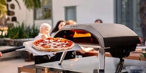 en pizza foran en pizzaovn og mennesker i bakgrunnen