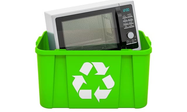 Kestävä kehitys - Rikkonainen mikroaaltouuni kierrätyslaatikossa