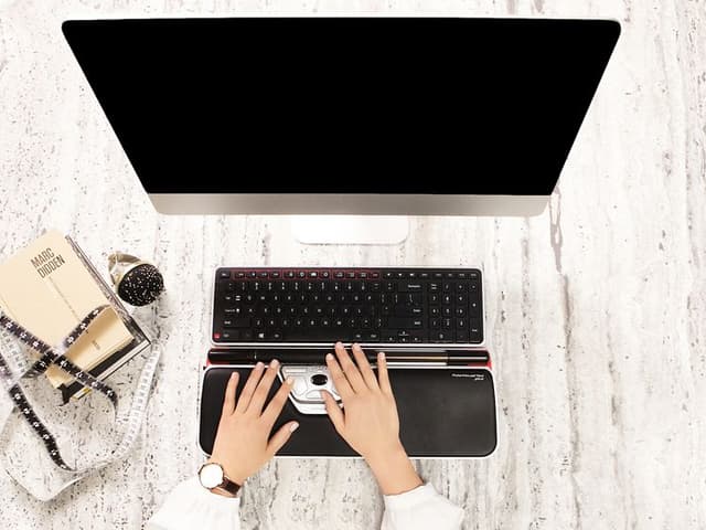 Henkilö työskentelee Contour-näppäimistöllä ja RollerMouse-hiirellä