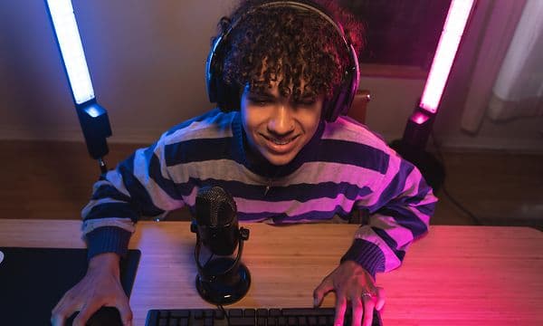 Gamer foran en skjerm med lys bak og mikrofon foran