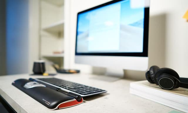 Contour RollerMouse ved siden av en skjerm og et headsett på en pult
