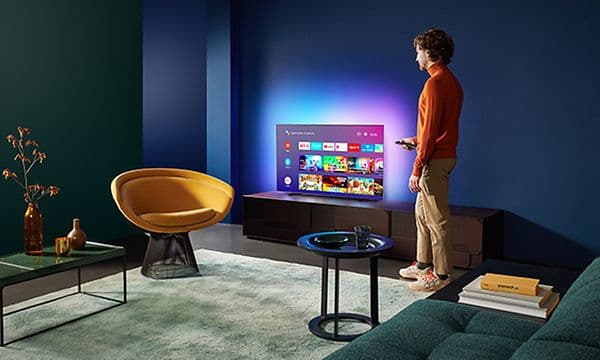 Mann står ved Ambilight-TV i stue