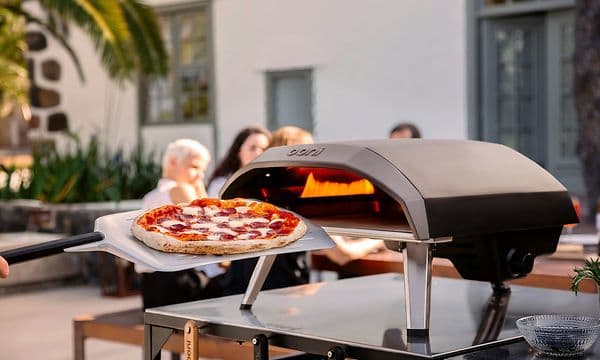 Pizza foran en pizzaovn som står på et bord utendørs