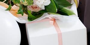 Blomsterbukett og hvit gaveboks med rosa bånd