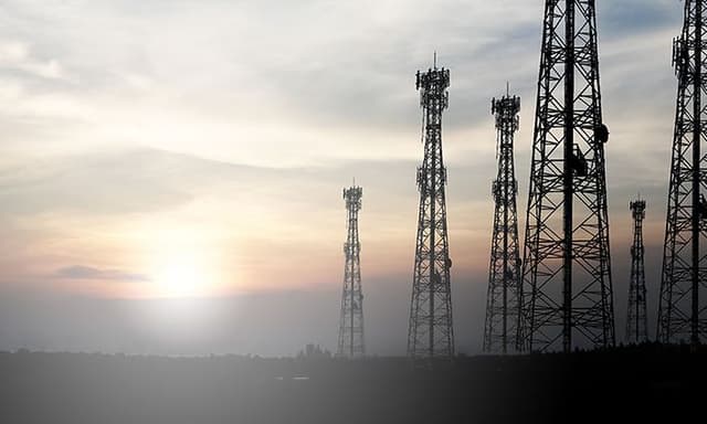 Telecom - 5G - En solopgang bag nogle høje 5G-master 1600x600