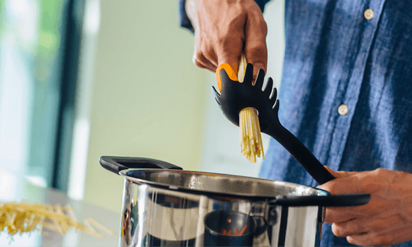 person putter spaghetti i en kaserolle ved hjelp av utstyr fra Fiskars