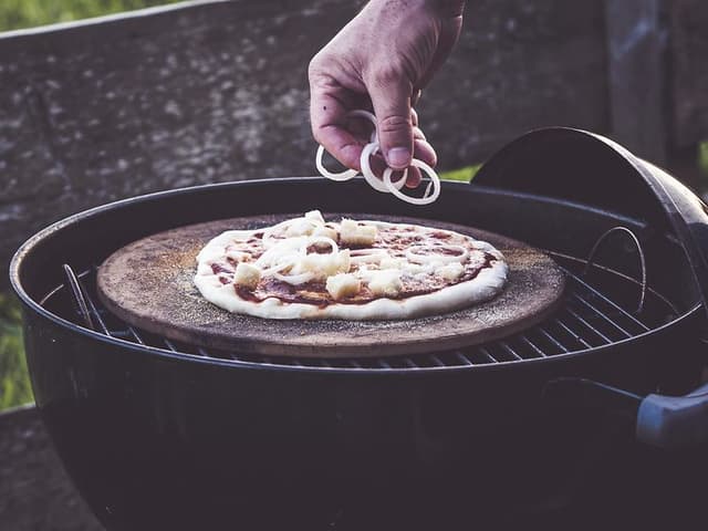 Hånd der putter fyld på pizza