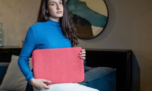 Kvinne i blå genser holder et rosa PC-etui