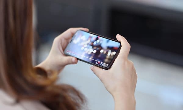Kvinne ser på film på smarttelefonen sin