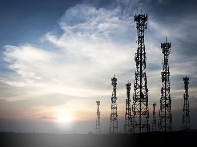 en soloppgang bak noen høye 5G-antenner