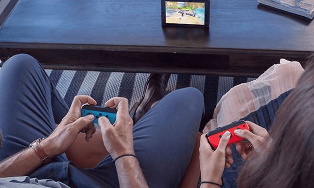 Nintendo Switch - kaksi henkilöä pelaa pöydällä olevalla laitteella sekä joycon-ohjaimilla
