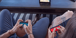 Nintendo Switch - kaksi henkilöä pelaa pöydällä olevalla laitteella sekä joycon-ohjaimilla