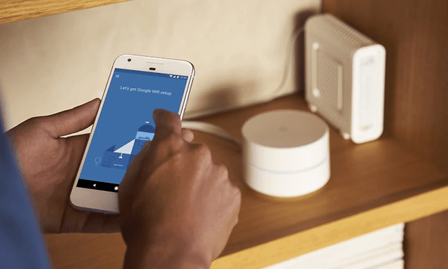 Mann installerer Google mesh-nettverk med telefon