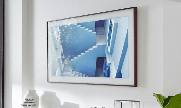 Närbild på en TV som sitter uppsatt på en vägg med ett grekiskt motiv som gör att den ser mer ut som en tavla. 