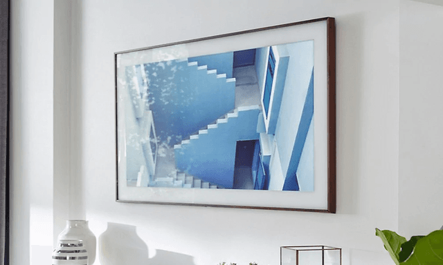 Närbild på en TV som sitter uppsatt på en vägg med ett grekiskt motiv som gör att den ser mer ut som en tavla. 