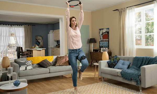 en kvinne som holder en Nintendo Ring fit og trener hjemme i stua