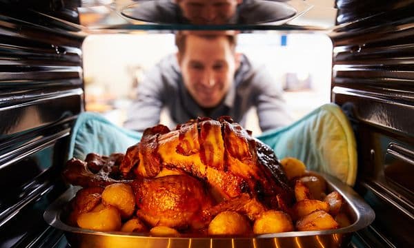 Mies ottaa grillatun kanan uunista 