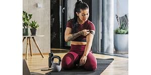 Pulssensor fra Polar på armen af kvinde, der sidder på gulvet med kettlebell